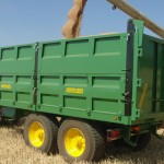 Remolque agrícola tándem de laterales cosechando con tractor John Deere